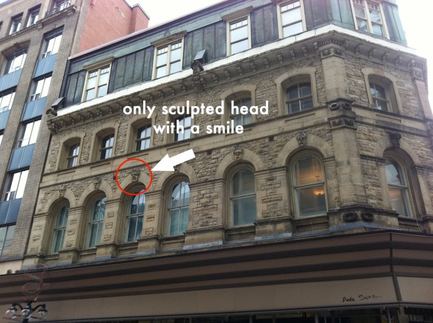 At 93 Sparks St. in Ottawa 11 scowling heads adorn a historic building. However, one of the heads is oddly smiling.